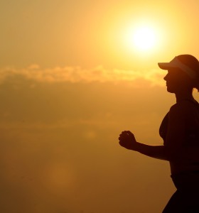 woman in hat running at sunset