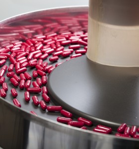 red capsules being sorted in a circular hopper