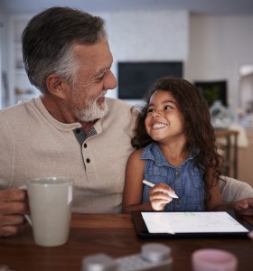 Happy Latinx grandfather with mug and granddaughter