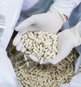 hands in sterile gloves holding manufactured white tablets