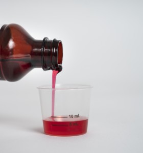 Liquid medicine being poured into a dosing cup