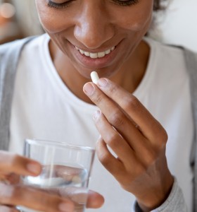 Young Woman Taking Dietary Supplement or Vitamin