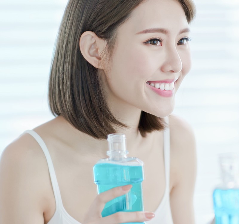East Asian American Woman Using Mouthwash
