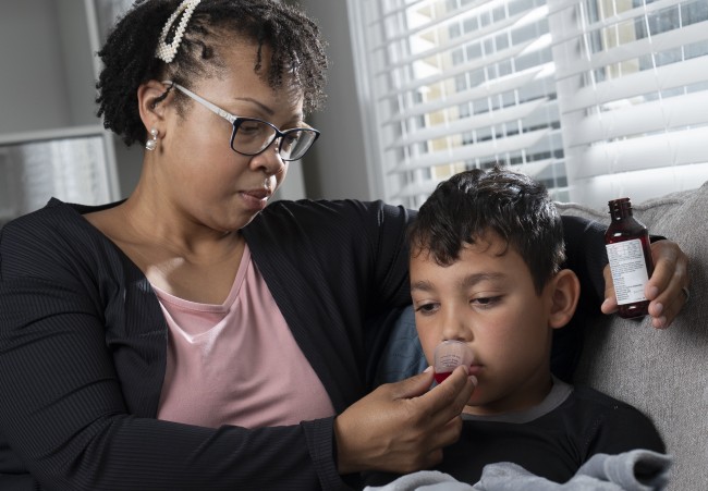 African American/Black Woman giving Hispanic/Latinx young boy liquid medicine