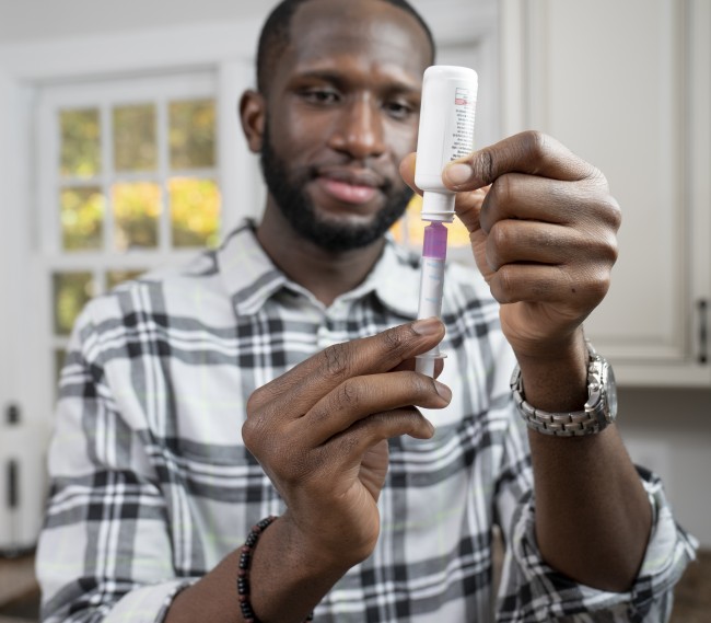 African American/Black man measuring liquid medicine