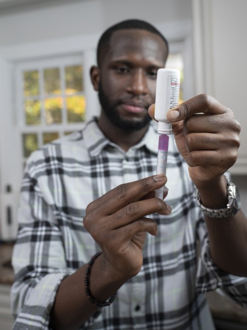 African American/Black man measuring liquid medicine