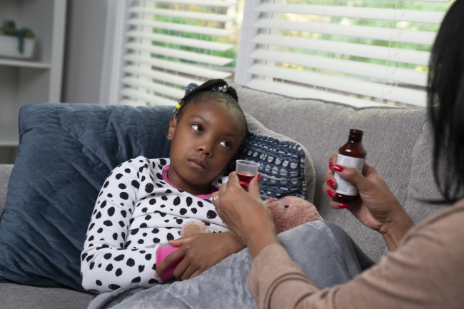 African American/Black woman giving sick African American/Black girl medicine