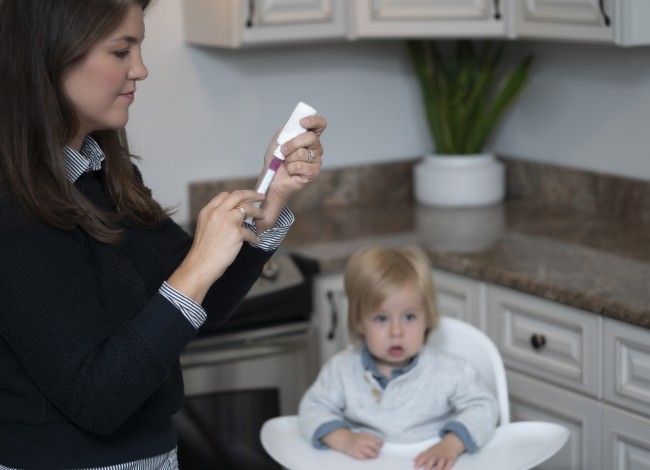 Caucasian/White Woman Measuring Liquid Dose for Caucasian/White Toddler in High Chair