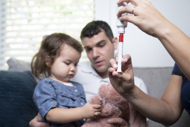 Man and woman giving toddler medicine