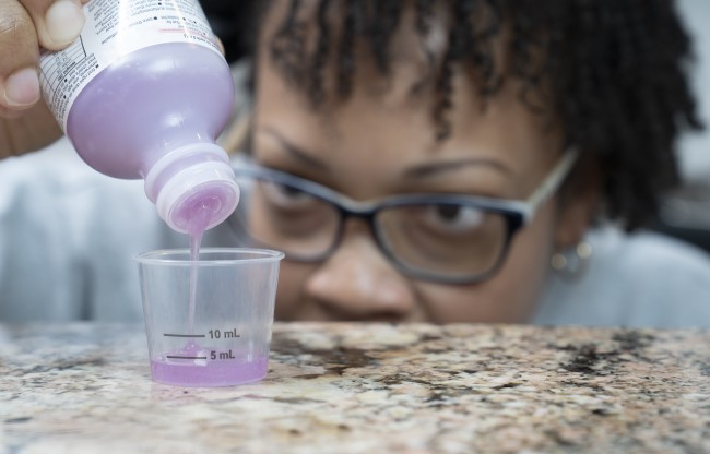 African American/Black woman measuring liquid medicine