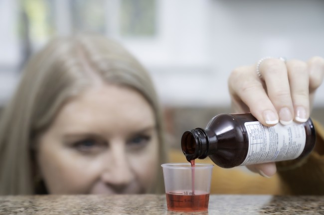 Blonde Caucasian/White woman measuring liquid medicine