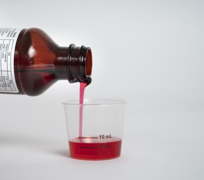 Liquid medicine being poured into a dosing cup