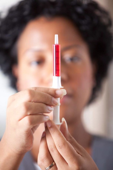 African American/Black woman measuring liquid medicine with syringe