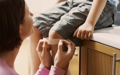 Woman Putting Bandaid on Child's Knee