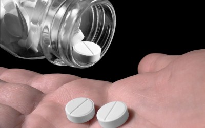 white tablets being shaken from a bottle into a hand white tablets being shaken from a bottle into a hand
