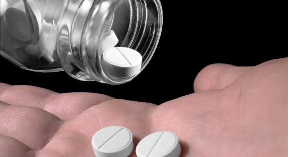 white tablets being shaken from a bottle into a hand