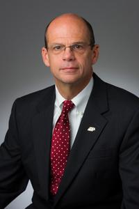 Studio headshot of Jeff Needham in suit and red tie