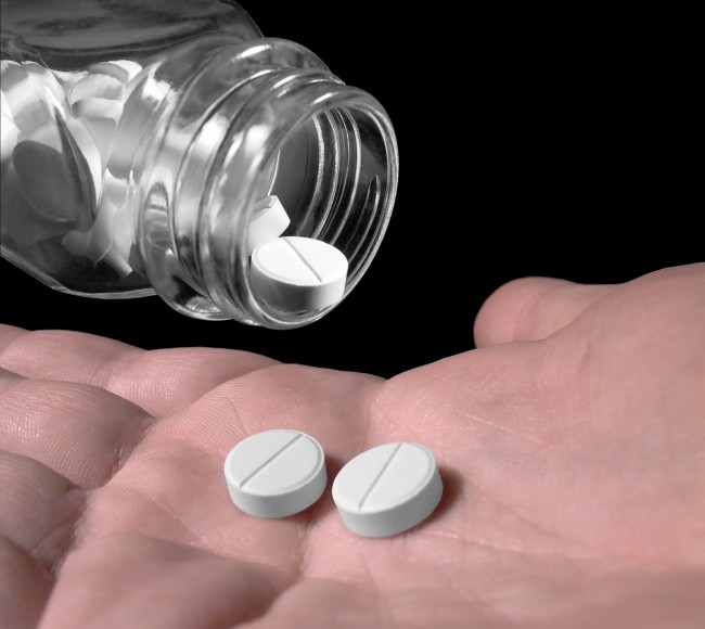 white tablets being shaken from a bottle into a hand